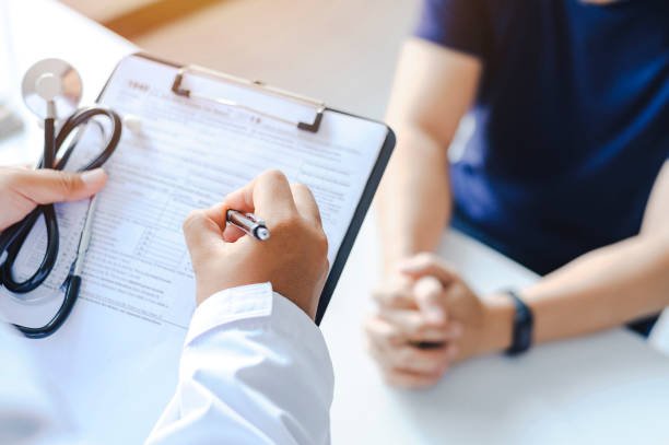 Close-up of a male doctor hand hold a silver pen and showing pad in hospital. Doctor giving prescription to the patient and filling up medical form at a clipboard